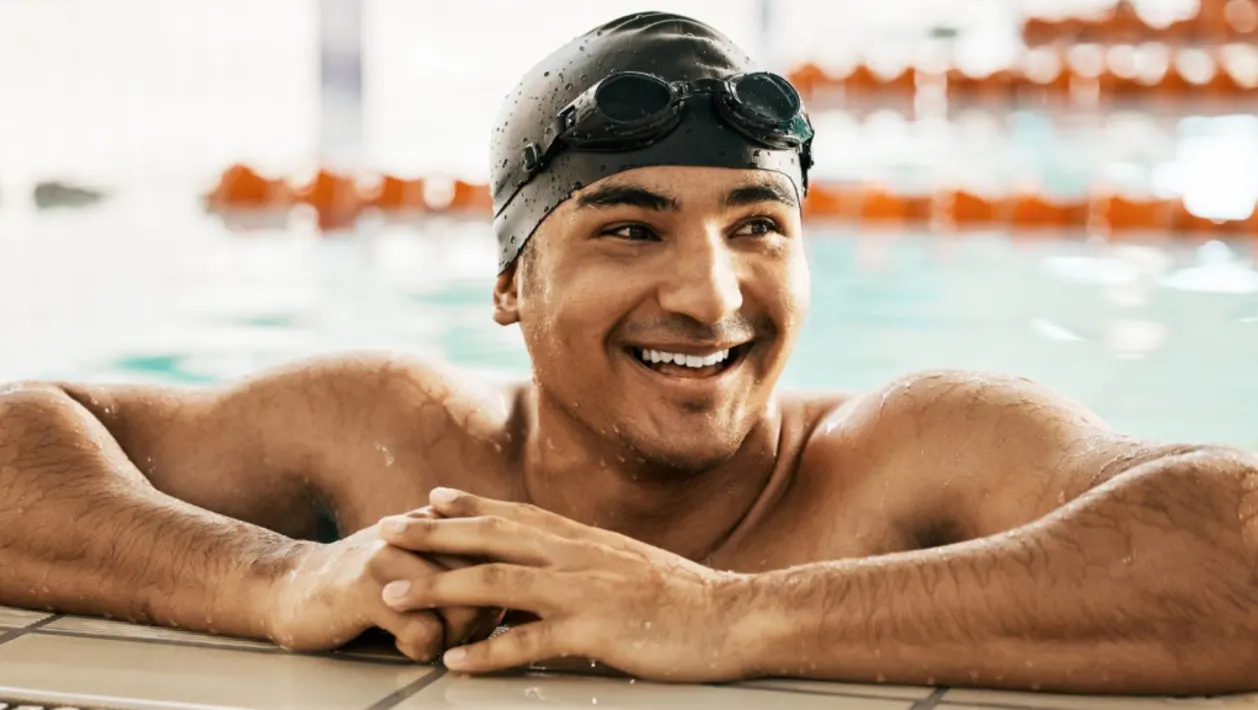 Smiling man in swimcap at side of pool